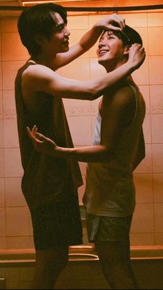 two people standing in front of a mirror with their hands on each other's head