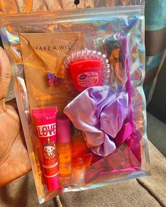 a person holding a clear bag with various items in it, including lip balm and lotion