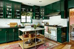 a kitchen with green cabinets and an island in the middle of the room, filled with pots and pans