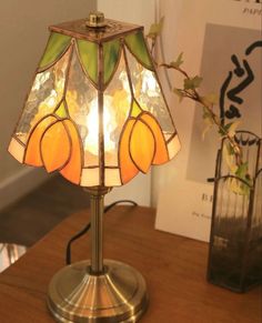 a lamp that is sitting on top of a wooden table next to a vase with flowers in it