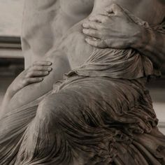 a man and woman embracing in front of a statue