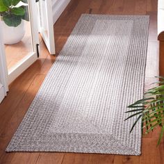 a living room area with hardwood floors and white trimming on the walls, along with a gray rug