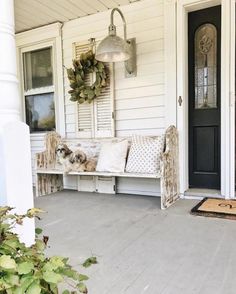 a bench sitting on the front porch of a house with wreaths hanging above it