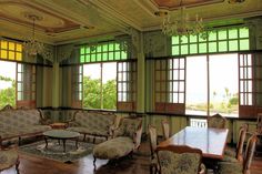 an ornately decorated living room with wooden floors and green walls, along with large windows that look out onto the ocean