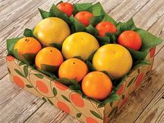 a cardboard box filled with oranges on top of a wooden table