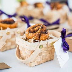 small baskets filled with pastries sitting on top of a white table covered in purple ribbons