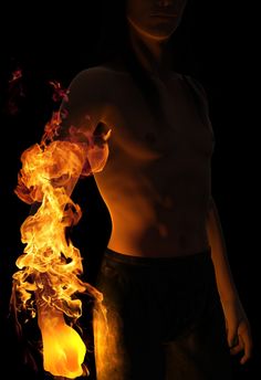 a shirtless man holding a lit object in his hand with flames coming out of it