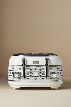 a white toaster sitting on top of a counter next to a brown wall with two black handles