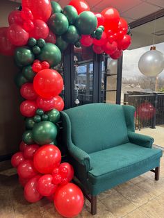 the balloon arch is decorated with red, green and silver balloons in an office lobby