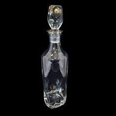 an empty glass bottle with a metal stopper on it's top, against a black background