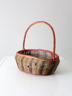 an empty basket sitting on top of a white table next to a black and red object