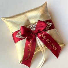 a gold pillow with a red ribbon and diamond brooch on it that says save the date