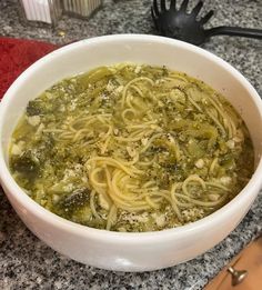 a white bowl filled with pasta and broccoli on top of a granite counter