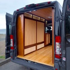 the back end of a van with its doors open and wood flooring in place