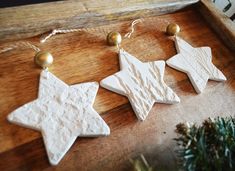 three white ceramic stars are hanging on a wooden table next to a christmas ornament