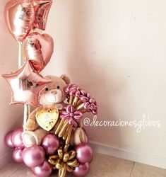 a teddy bear sitting on top of some balloons and other items in front of a wall