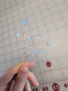 someone is working on something that looks like a star ornament with blue glass beads