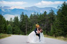 a bride and groom kissing in the middle of an empty road with mountains in the background