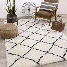 a living room area with a chair, rug and plant in the corner on the floor