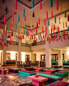 colorful decorations hang from the ceiling in a large room filled with tables and couches