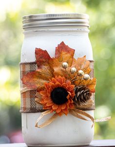 Decorative wide mouth Mason Jar painted in white color, hand painted Mason Jar décor for fall. These jars can be used as centerpiece on the tables , for storing dry items or as gifts . 12 quart 32 ounces  mason jars with wide mouth lid/band, hand painted in white color, decorated with orange plaid ribbon, twine bow ,artificial maple leaf ,sunflower, pine cone and golden beads.   These jars are painted using various coats of chalk paint,destressed and then sealed by waterproof wax coat. Please ke Crafts Using Glass Jars, Fall Wedding Mason Jar Centerpieces, Firefly Mason Jar Craft, Decorated Mason Jars Diy, Fall Jars Decorations, Fall Craft For Women, Fall Mason Jar Ideas, Fall Decor Ideas For Office Desk, Decorate Candle Jars