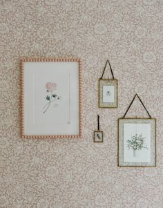 three framed pictures hang on the wall next to two small frames with flowers in them