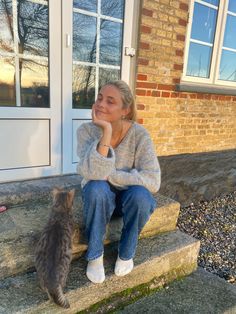 a woman sitting on steps next to a cat