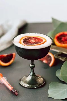 blood oranges in a goblet on a table with leaves and syringles