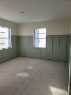 an empty room with two windows and no one in the room on the far side