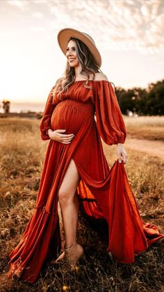 a pregnant woman in an orange dress and hat poses for the camera with her legs spread out