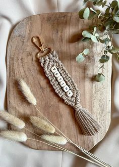 a key chain with the word bead on it sitting next to some dried plants