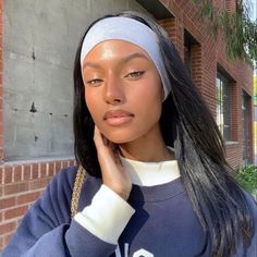 a woman with long black hair wearing a white headband and looking at the camera