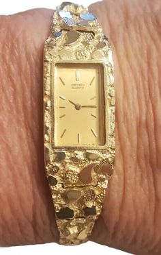 This vintage Seiko wristwatch is a stunning piece of luxury for women. The watch features a polished yellow gold case with a hidden fold clasp closure and a two-piece strap with a maximum wrist size of 6.26-6.75 inches. The cushion-shaped watch face is set with a beautiful gold bezel, and the watch is water-resistant. The watch has a quartz movement and a 12-hour dial, with an unknown number of jewels and year of manufacture. It comes with its original box and packaging, and is a rare find for collectors. The watch has a fixed bezel type and a solid caseback. It is a perfect addition to any dress/formal outfit and is sure to catch the eye of admirers. Bracelet Watches Women Vintage Style, Gold Rectangular Jewelry For Anniversary, Gold Rectangular Watch With Box Clasp, Elegant Gold Engraved Watches, Engraved Yellow Gold Watches For Anniversary, Formal Engraved Gold Jewelry And Watches, Collectible Gold Watches With Polished Finish, Gold Jewelry Watch With Rectangular Dial For Anniversary, Antique Gold Rectangular Jewelry And Watches