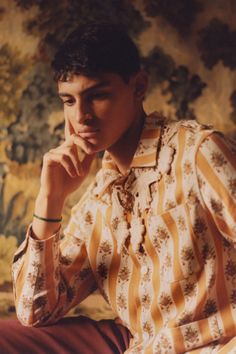 a man sitting on a chair with his hand under his chin and looking at the camera