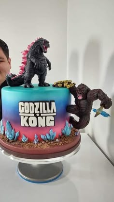 a man standing next to a cake with godzillas on it and the words godzilla kong