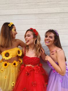 three young women dressed in colorful costumes posing for the camera with their arms around each other