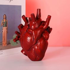 a red heart statue sitting next to a book