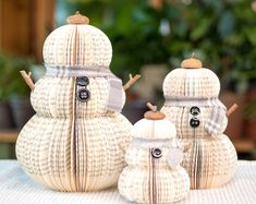 two snowmen made out of book pages sitting on top of a table next to each other