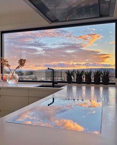 the sky is reflecting in the water on the kitchen counter top, as the sun sets over the ocean