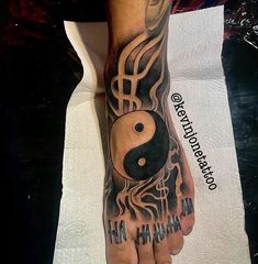 a person with a tattoo on their foot and hand holding a yin - yang symbol