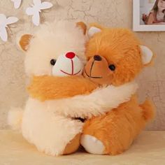 two teddy bears hugging each other on a bed