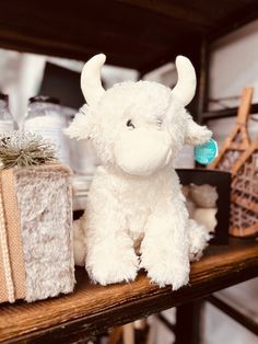 a white stuffed animal sitting on top of a wooden shelf next to wrapped gift boxes