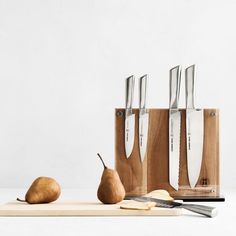 three knives and two pears on a cutting board