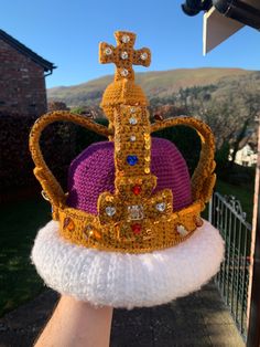 a hand is holding a crocheted crown