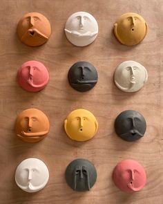 six different colored ceramic faces on a wooden surface