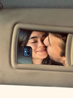 a man and woman kissing in the back seat of a car while taking a selfie