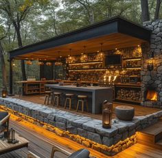 an outdoor bar is lit up at night with candles on the counter and stools