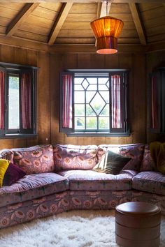 a living room filled with furniture next to two windows and a rug on the floor