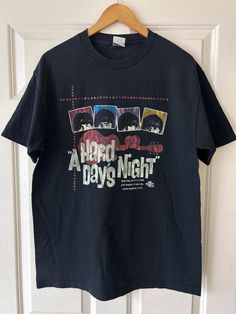 a black t - shirt with the words hard days night on it hanging from a door