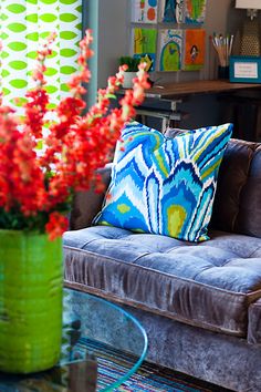 a living room filled with furniture and lots of red flowers in a vase on top of a coffee table